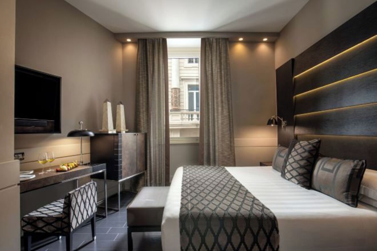 Une chambre d’hôtel moderne équipée d’un lit, d’un bureau, d’une télévision et offrant une vue sur la ville.