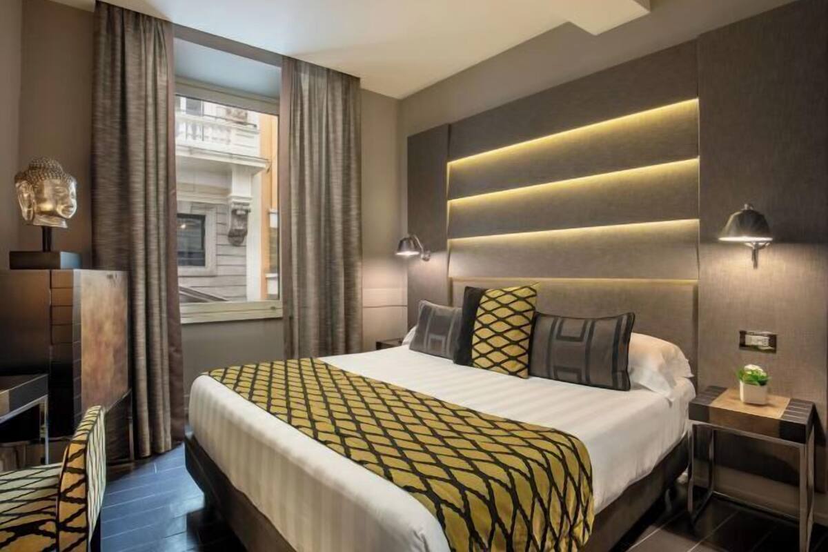 A modern hotel room with a large bed, a desk, and a view of the city.