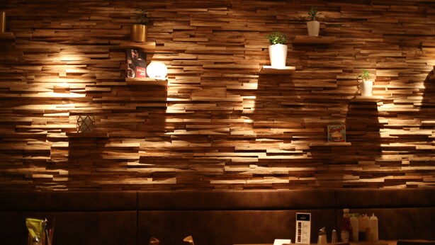A restaurant with a wooden wall design, cushioned seating, and tables with condiments and menus. - Hotel FIVE (Nuremberg)