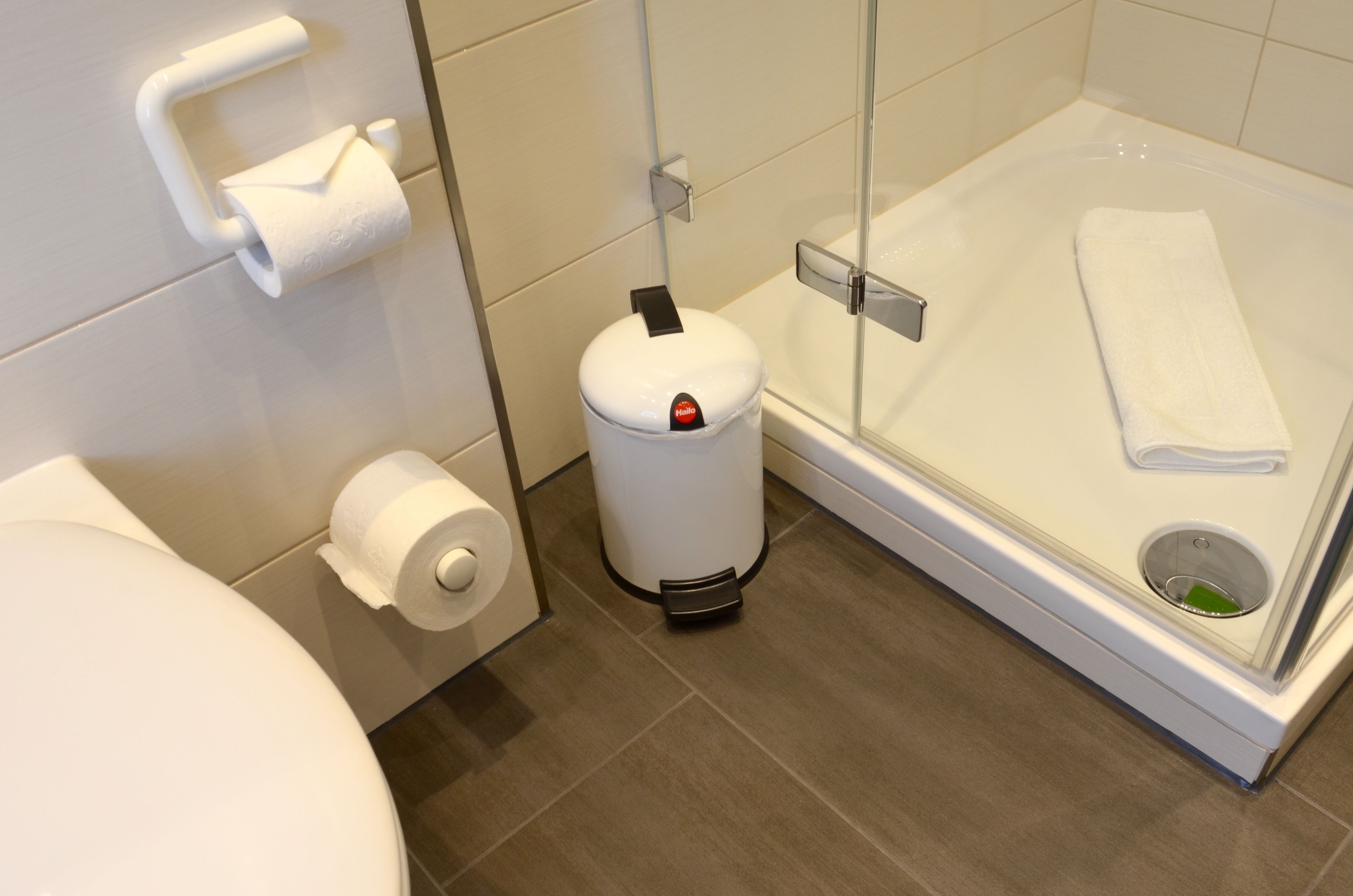 Ein modernes Badezimmer mit Toilette, Mülleimer und einer Duschkabine.