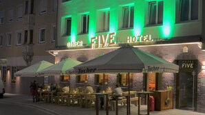 The exterior of the Five Hotel with outdoor seating and a prominent illuminated sign. - Hotel FIVE (Nuremberg)
