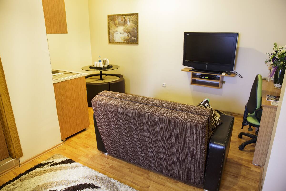 Una habitación pequeña con sofá, una mesita con tazas, un televisor y una silla.