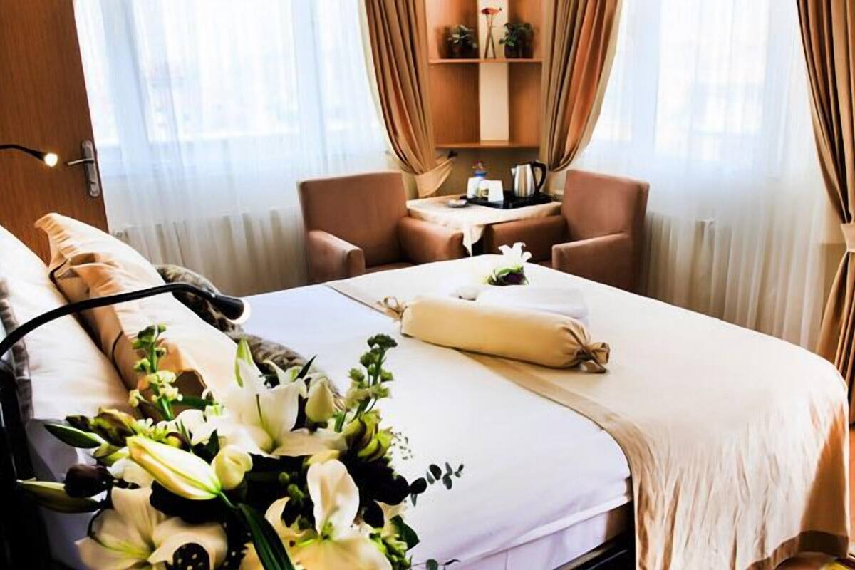Una habitación de hotel con cama, mesita de noche, una silla y un pequeño escritorio.