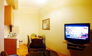 Um espaço compacto com cozinha compacta, área de refeições e televisão.