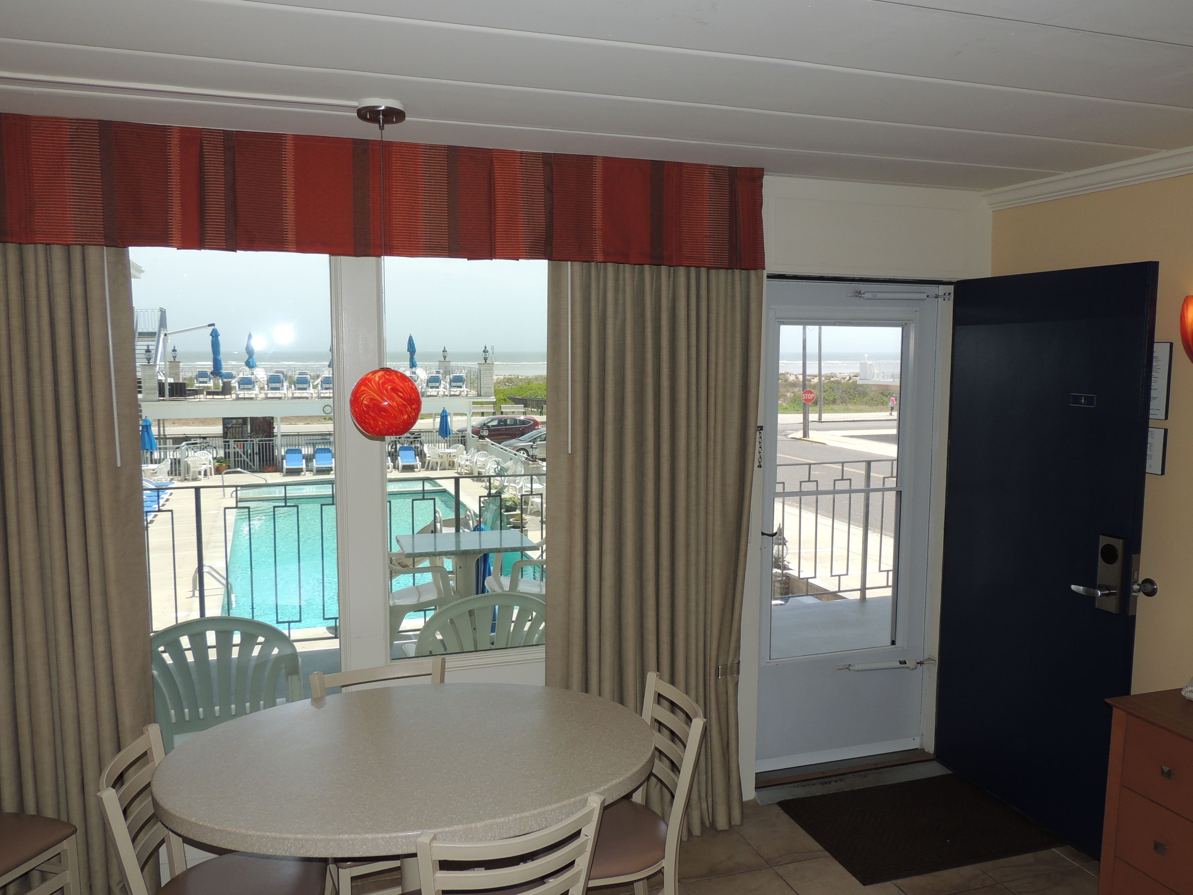 A room with a pool view, a dining table with chairs, a door, and a small cabinet.