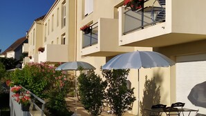 Una hilera de casas urbanas con balcones, mobiliario exterior y jardineras con flores.