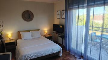 A bedroom with a bed, bedside lamps, a TV, a mirror, and a view of the outdoors.