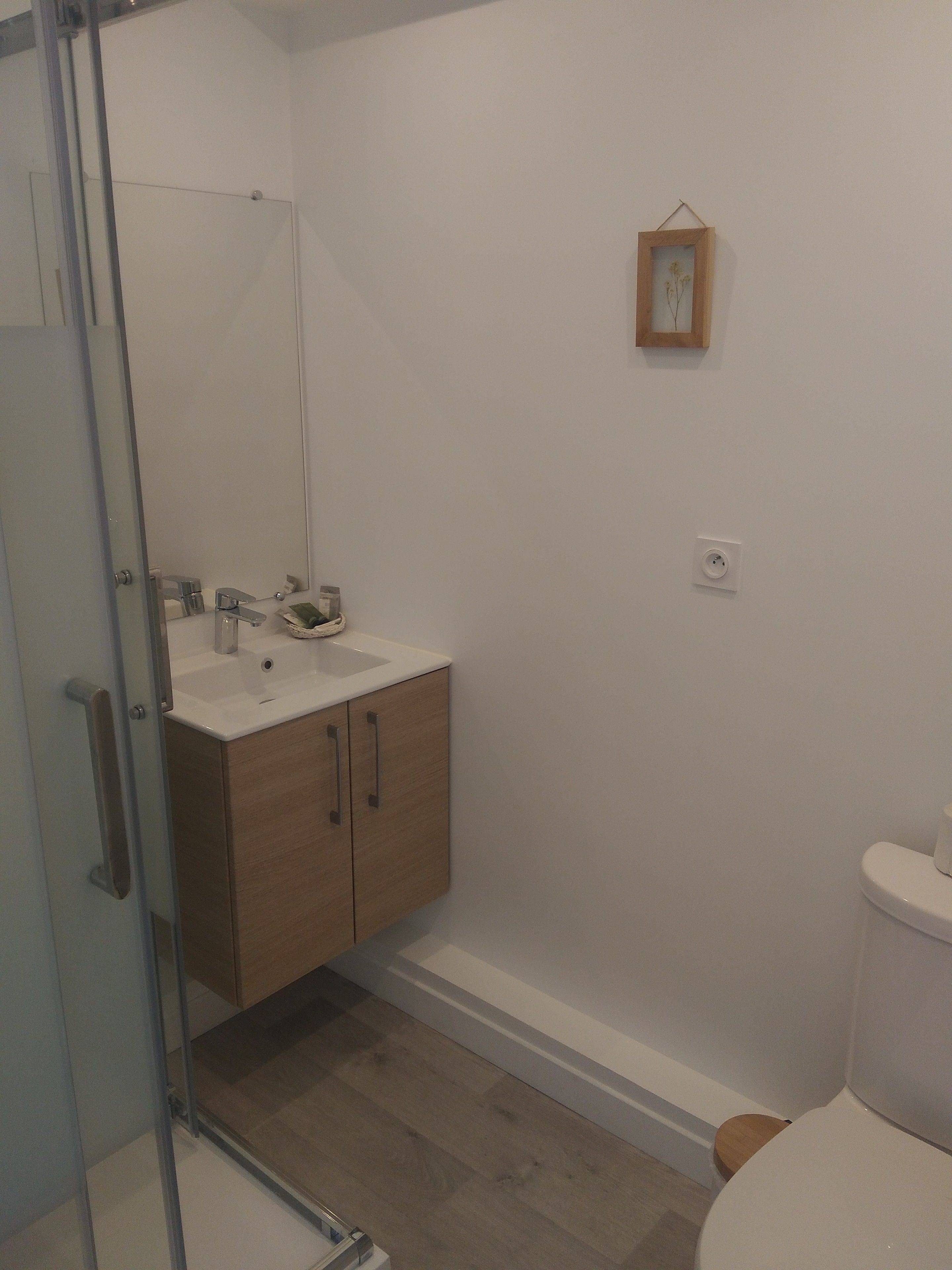 Ein Badezimmer mit Glasdusche, einem Holzwaschtisch mit Waschbecken und einer Toilette.