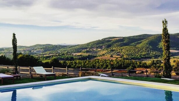 A swimming pool with a view of rolling hills and a cloudy sky. - Pietriccio Rosso (Manciano)