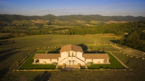 A large, single-story building with a tiled roof, surrounded by well-maintained gardens and fields. - Pietriccio Rosso (Manciano)