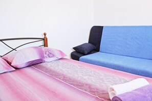 Una cama con una colcha estampada, un sofá azul y un cabecero de madera.