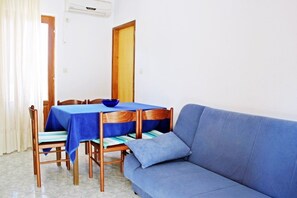 Un comedor con una mesa dispuesta para cuatro personas, un sofá azul y una puerta de madera.