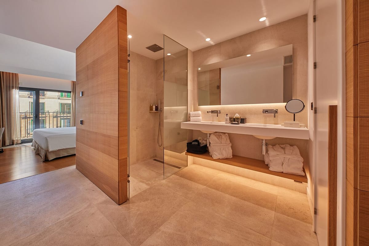 Een moderne badkamer met een douchecabine van glas, een grote spiegel en een wastafelmeubel met een wastafel en handdoekhouder.