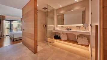 A modern bathroom with a glass shower enclosure, a large mirror, and a vanity with a sink and towel rack.