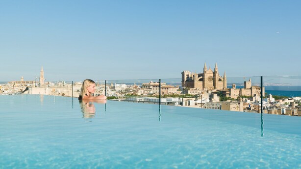 Una piscina con vistas a la ciudad, que incluye una catedral imponente y un castillo.