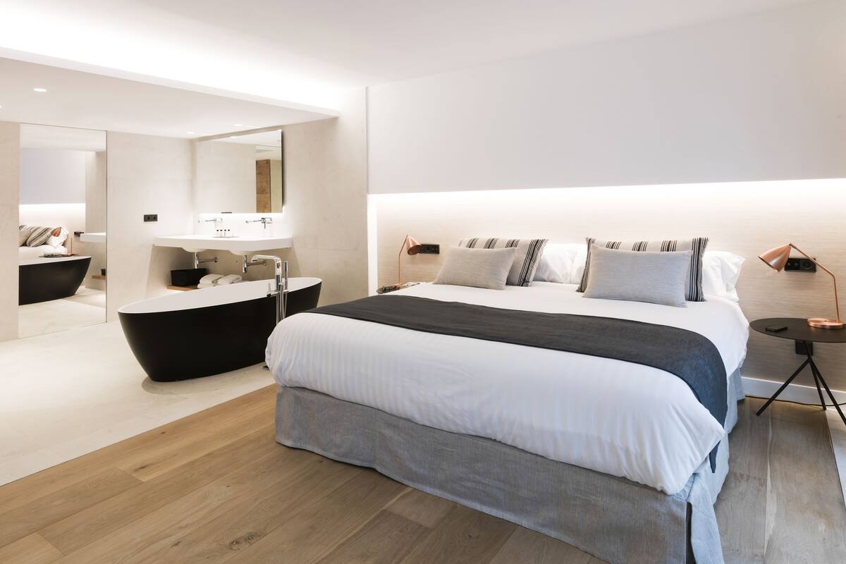 Een moderne slaapkamer met een groot bed, een ingebouwd bad en een grote spiegel.