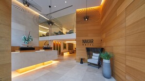Un moderno vestíbulo de hotel con un mostrador de recepción, paneles de madera y un cartel que dice "NAKAR HOTEL".