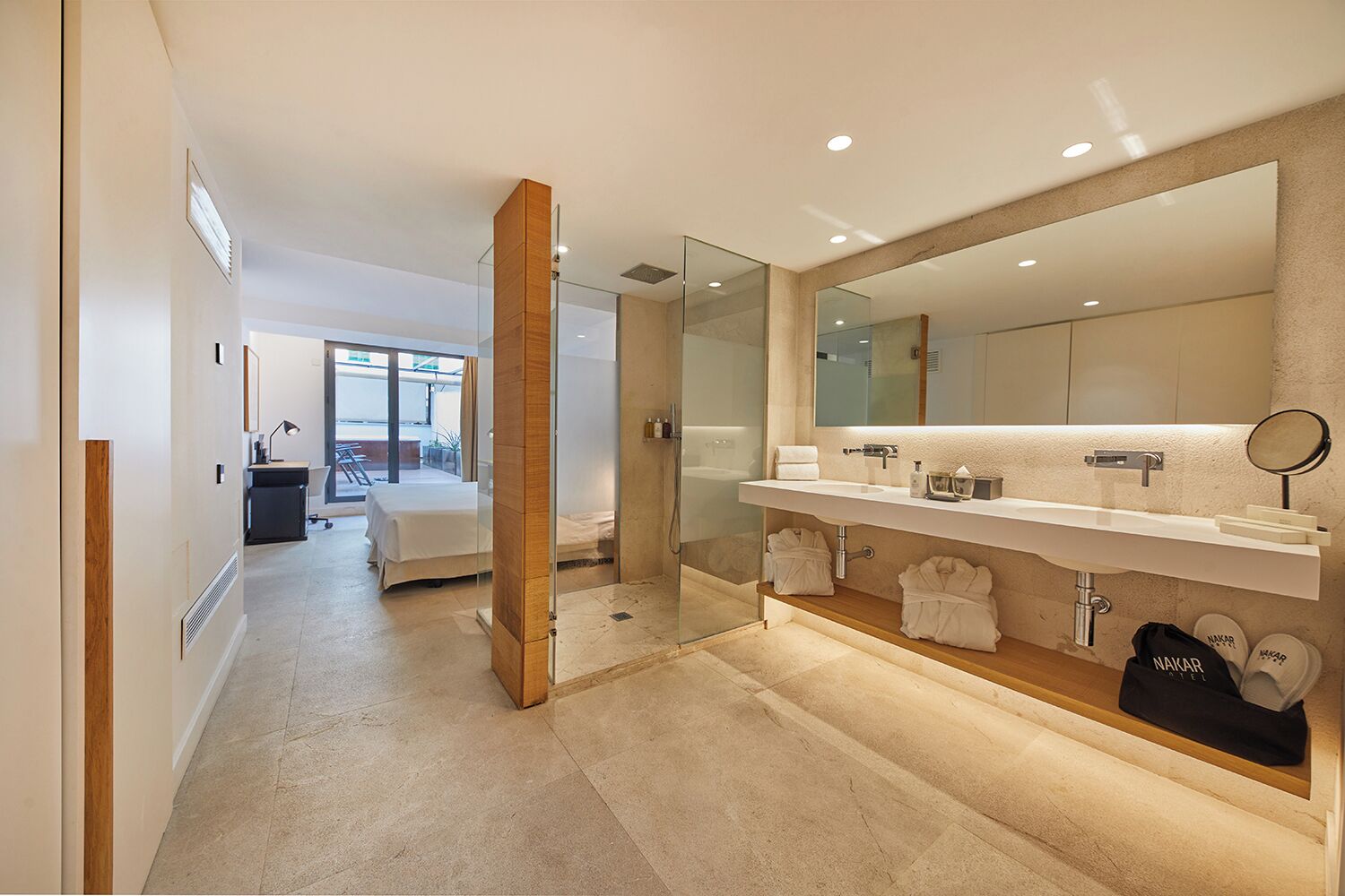 Une salle de bain d’hôtel moderne, dotée d’un grand miroir, d’une baignoire et d’une douche.