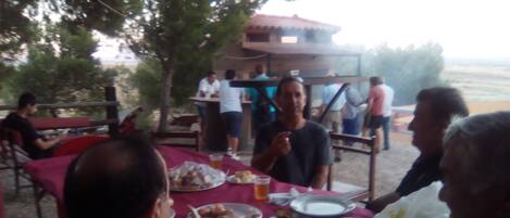 A group of people dining outdoors at a table with plates of food and drinks.