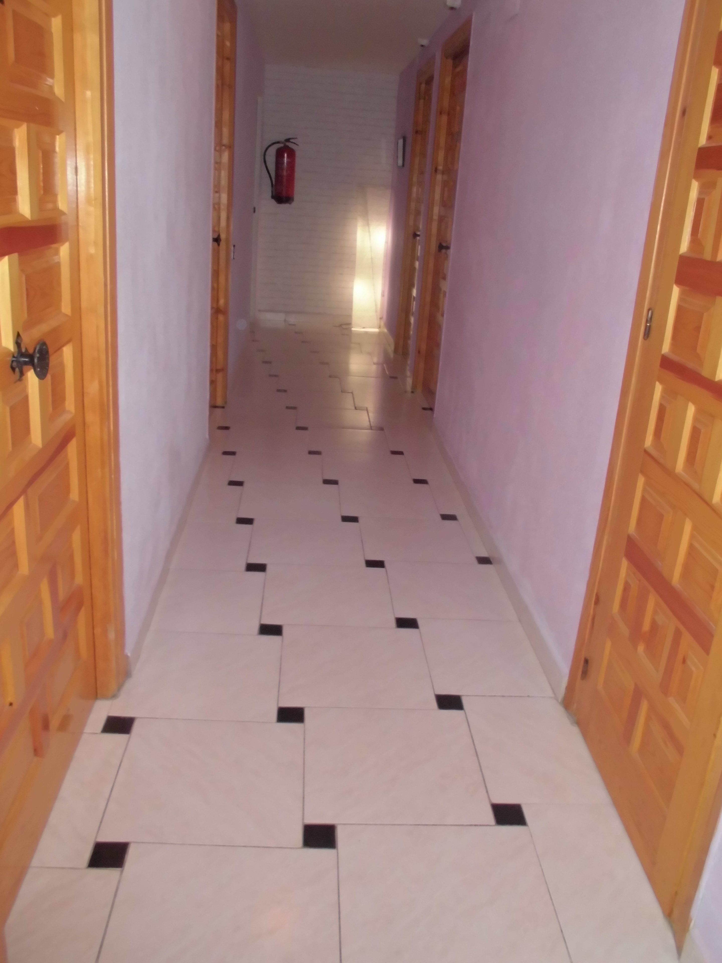 Un pasillo con baldosas de diseño y puertas de madera.