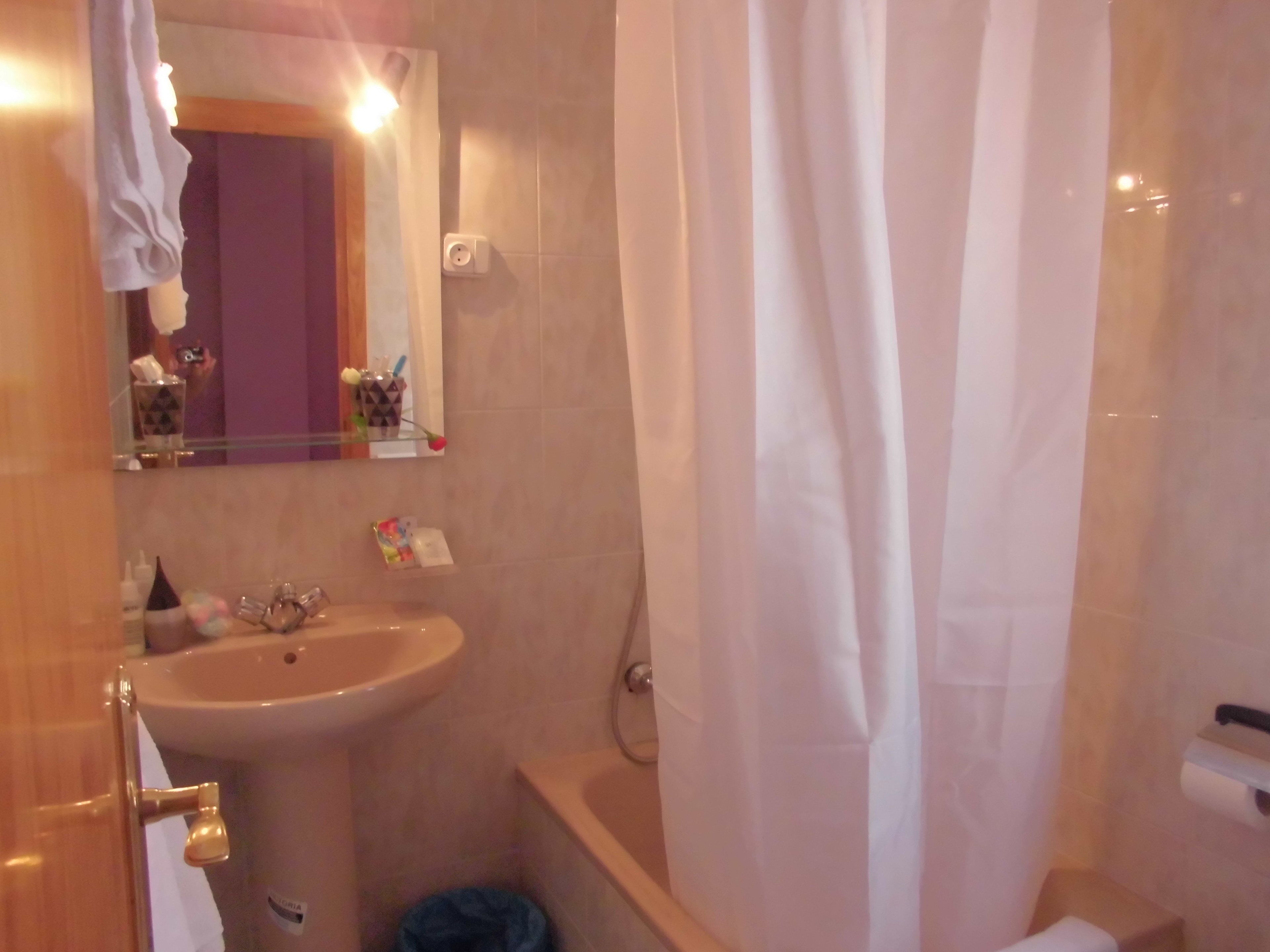 A bathroom with a sink, mirror, and shower curtain.