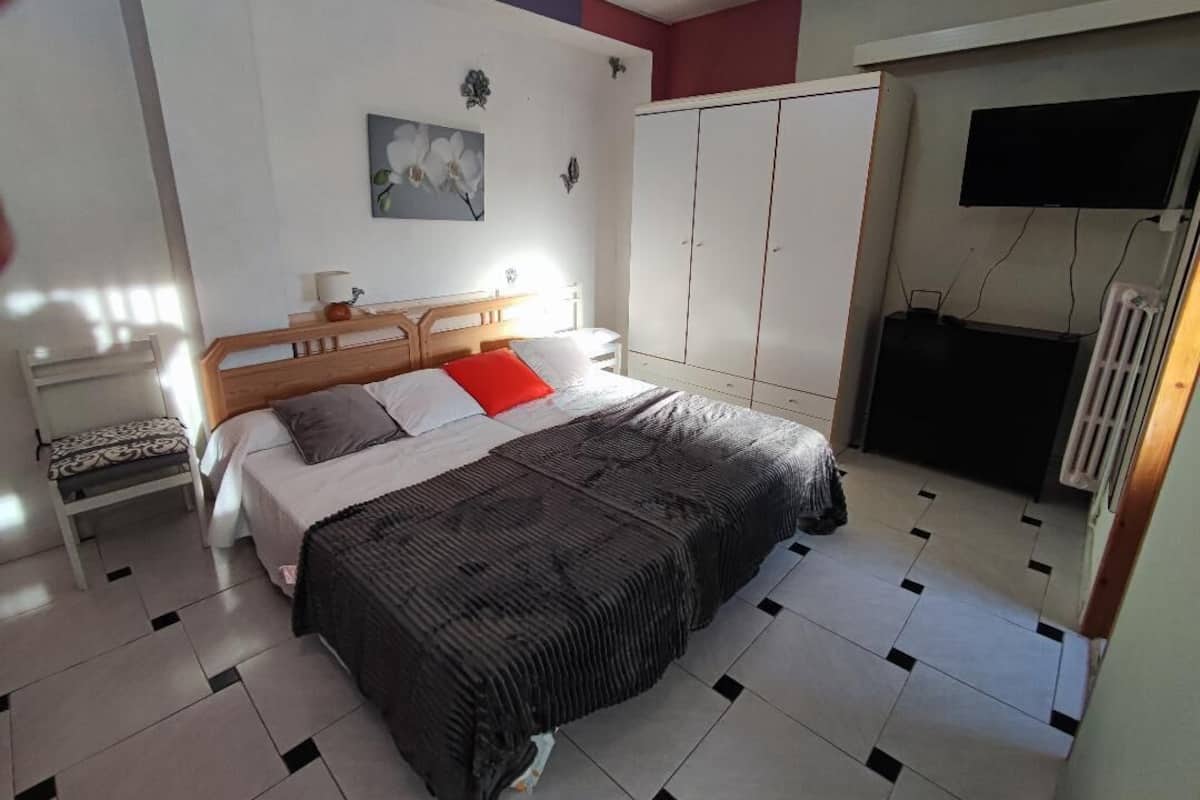 Een slaapkamer met een bed, nachtkastje, kledingkast en een televisie.