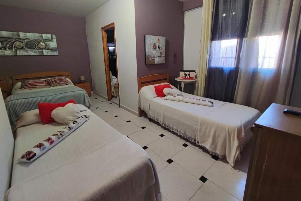 Een hotelkamer met twee eenpersoonsbedden, een tafeltje, een stoel, een bureau en een raam met gordijnen.