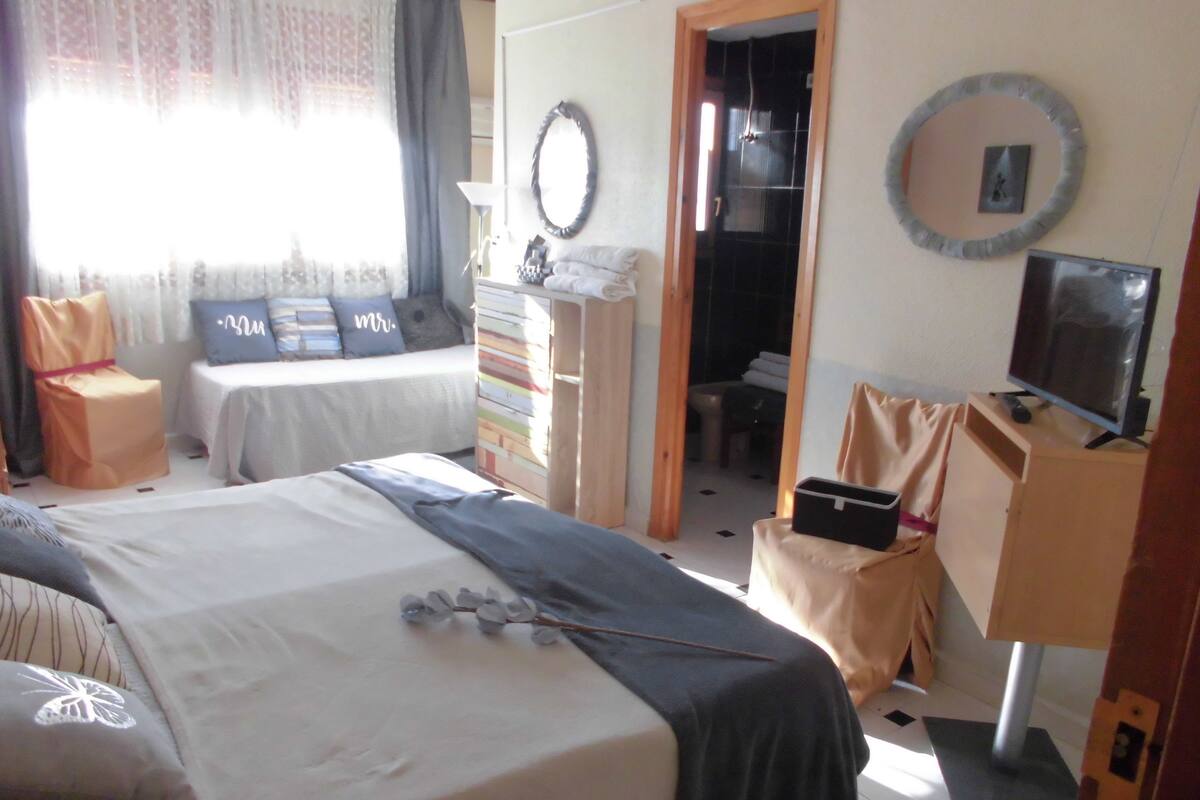 Een hotelkamer met een bed, een bureau, een stoel, een televisie en een kledingkast.