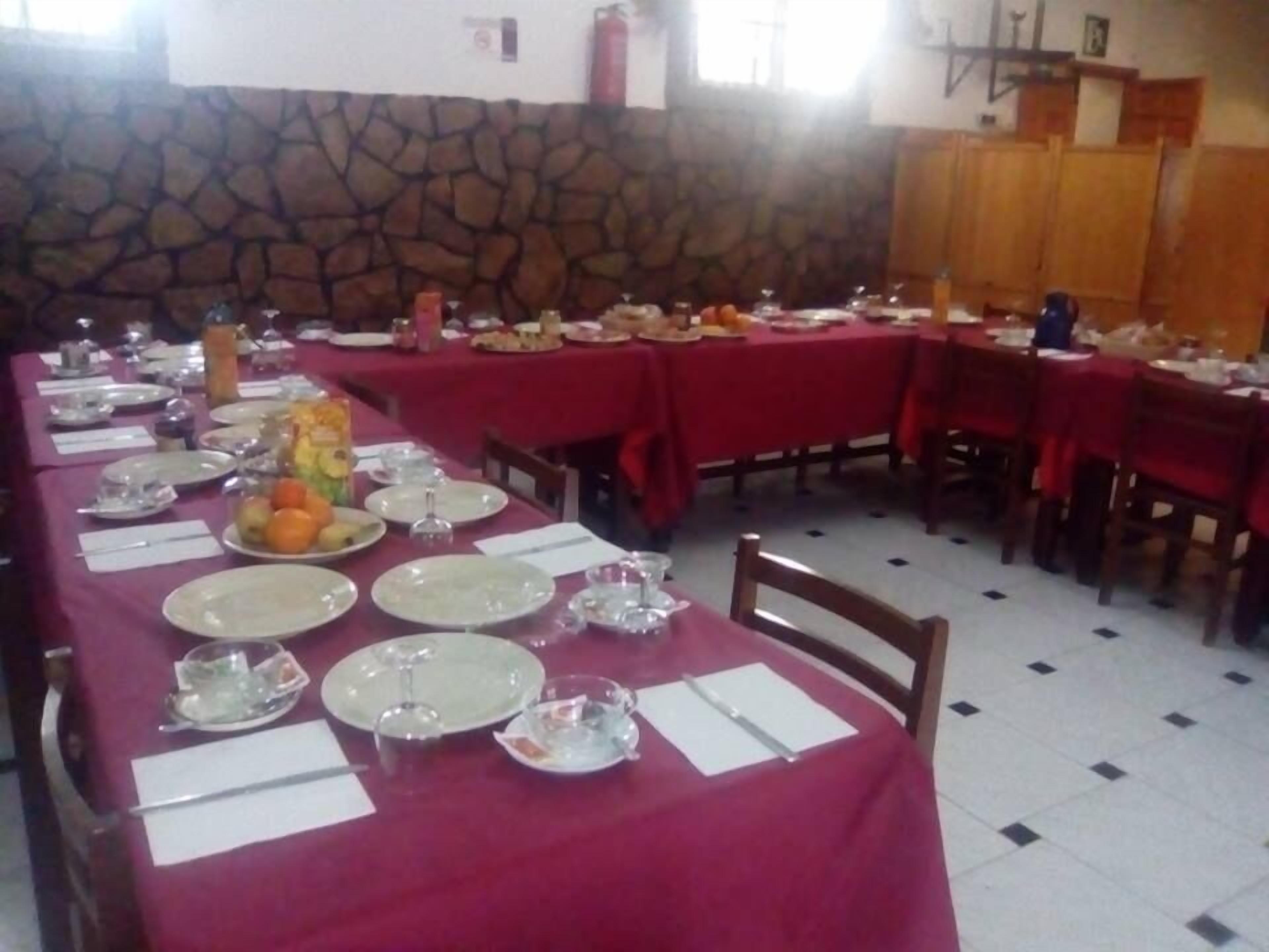 A dining area with tables set for a meal, stone wall, and a fire extinguisher on the wall.