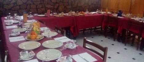 A dining area with tables set for a meal, stone wall, and a fire extinguisher on the wall.