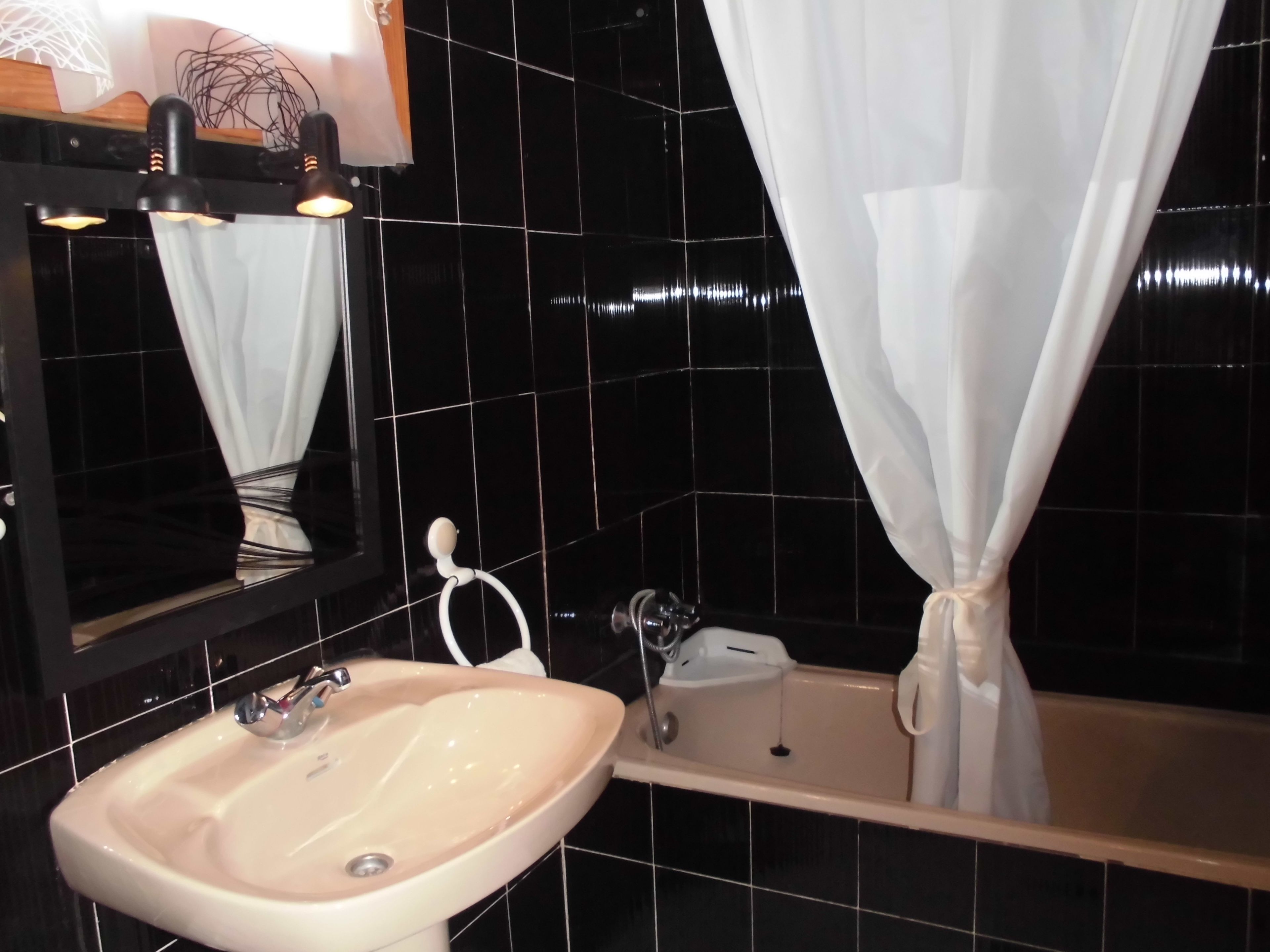 A bathroom with a sink, mirror, and bathtub.