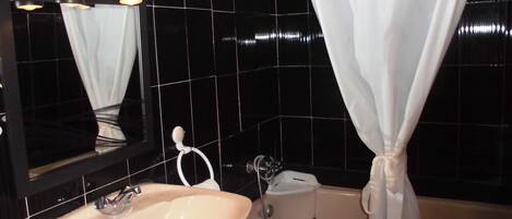 A bathroom with a sink, mirror, and bathtub.