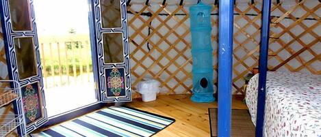 A tent with a bed, a window, a blue ladder, and a blue toilet.