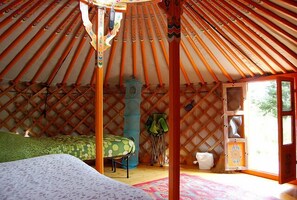 Uma yurta com cama, uma mesa pequena e uma janela.