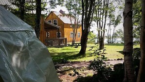 Una casa de madera con un porche y una mesa de picnic en un área boscosa.