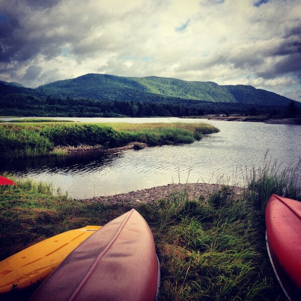A river with boats and a mountain in the background. - Cabot Shores Wilderness Resort (Indian Brook)