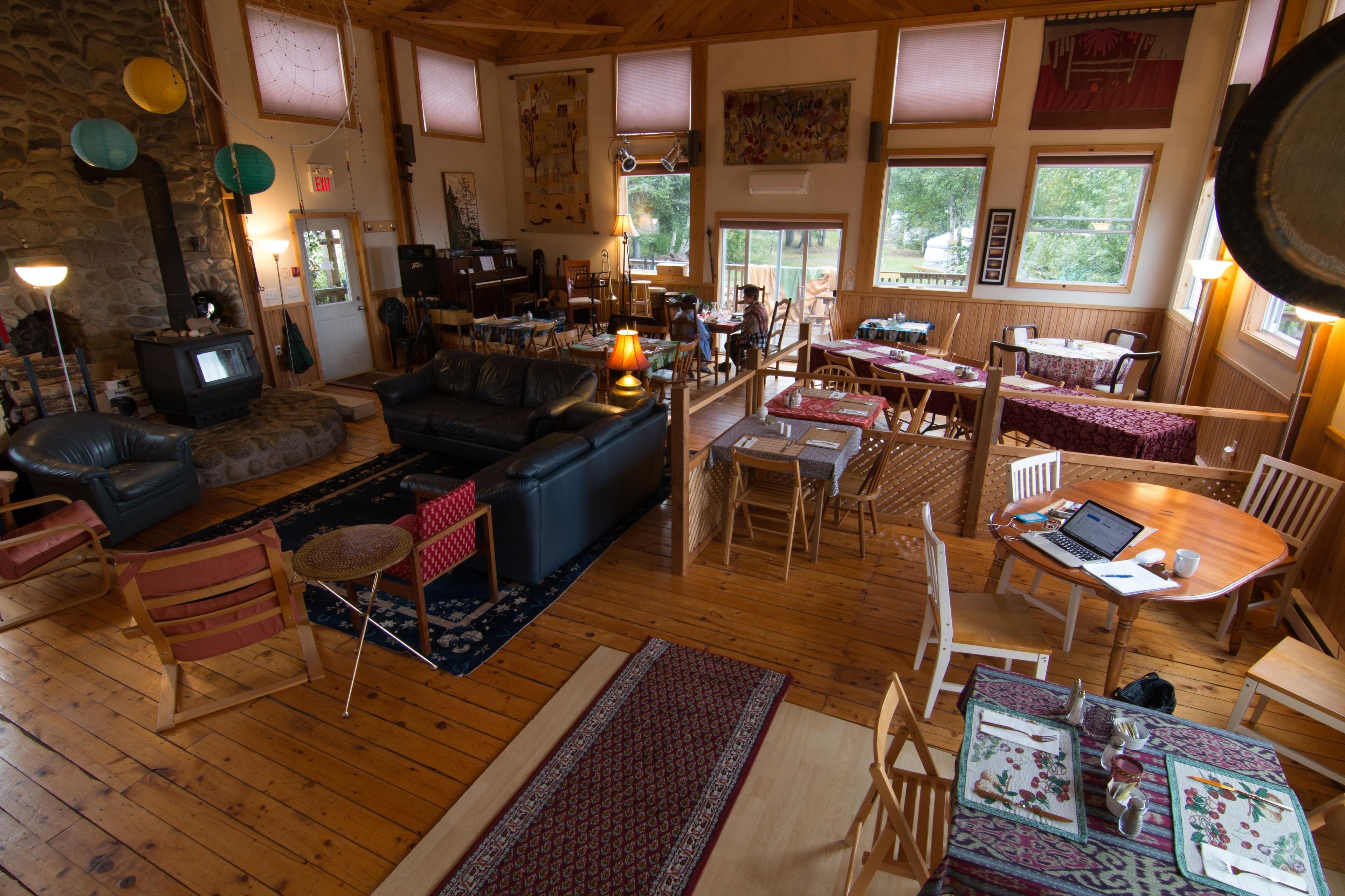 Una sala de estar acogedora con piso de madera, chimenea, asientos y un comedor con una laptop sobre la mesa.