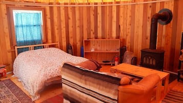 Una habitación acogedora con cama, sofá, mesa, estantería y estufa de leña.