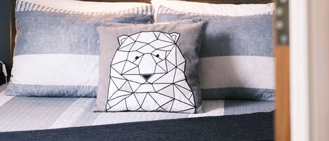 Una cama bien hecha con ropa de cama a rayas y un diseño geométrico de almohada.