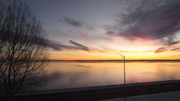 Solnedgang over et roligt vandareal med en lygtepæl i forgrunden.