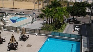 A rooftop swimming pool with lounge chairs and umbrellas, overlooking a beach and ocean. - Betel Beach Class Internacional (Recife)