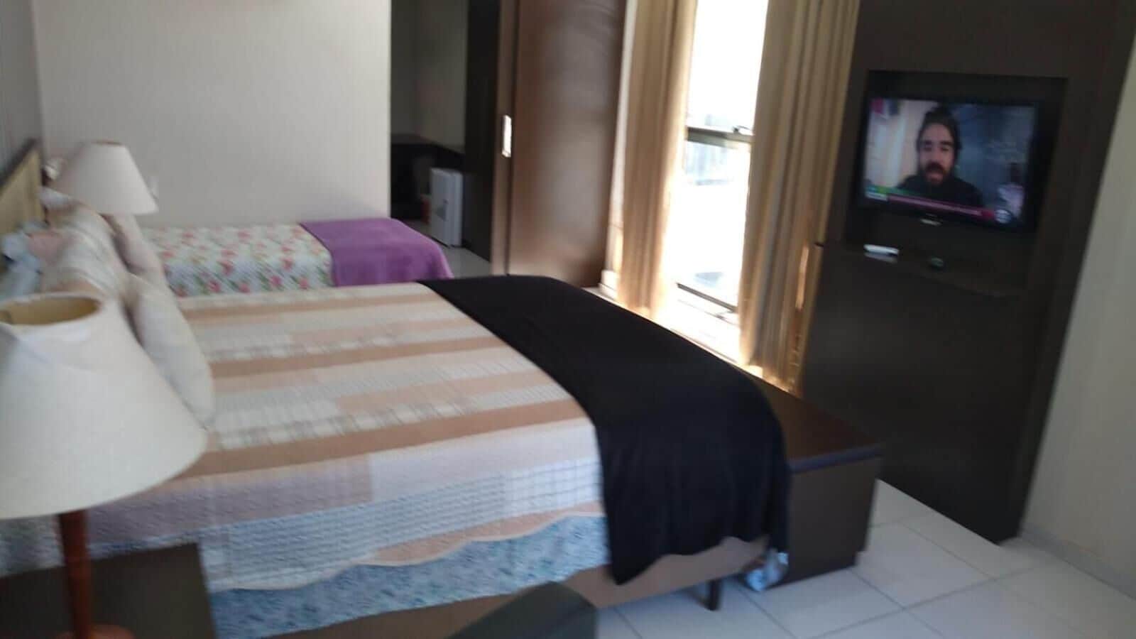 Una habitación de hotel con cama, escritorio, lámpara y televisor.