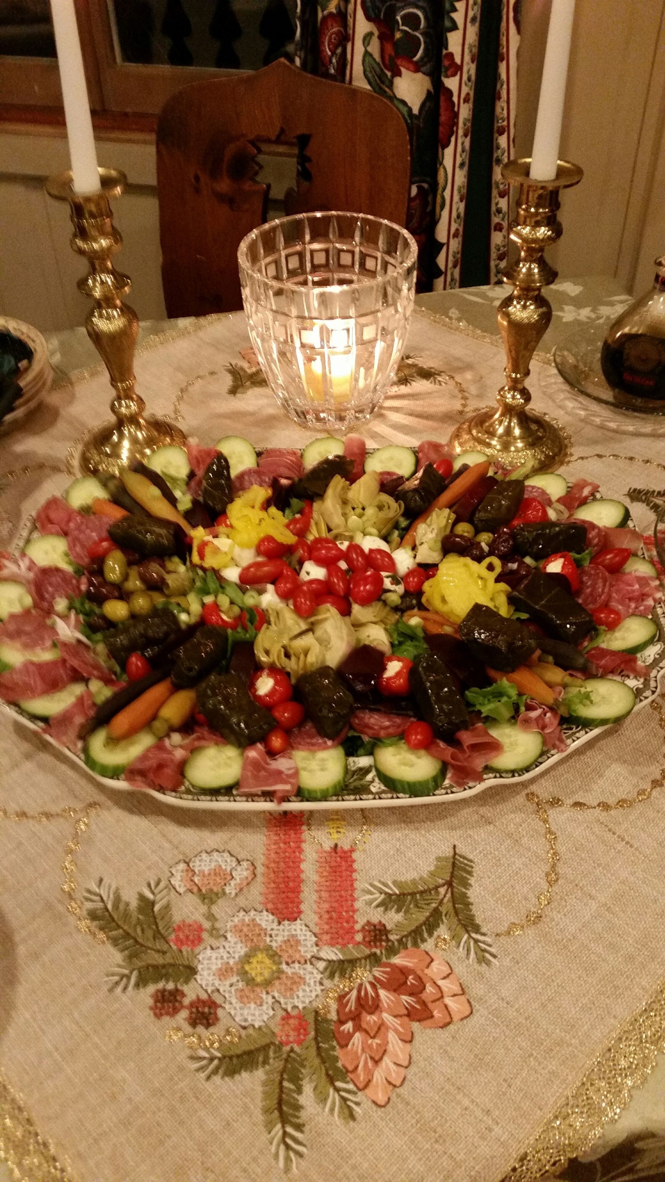 A table with a floral tablecloth, a glass candle holder, and a platter of stuffed vegetables.