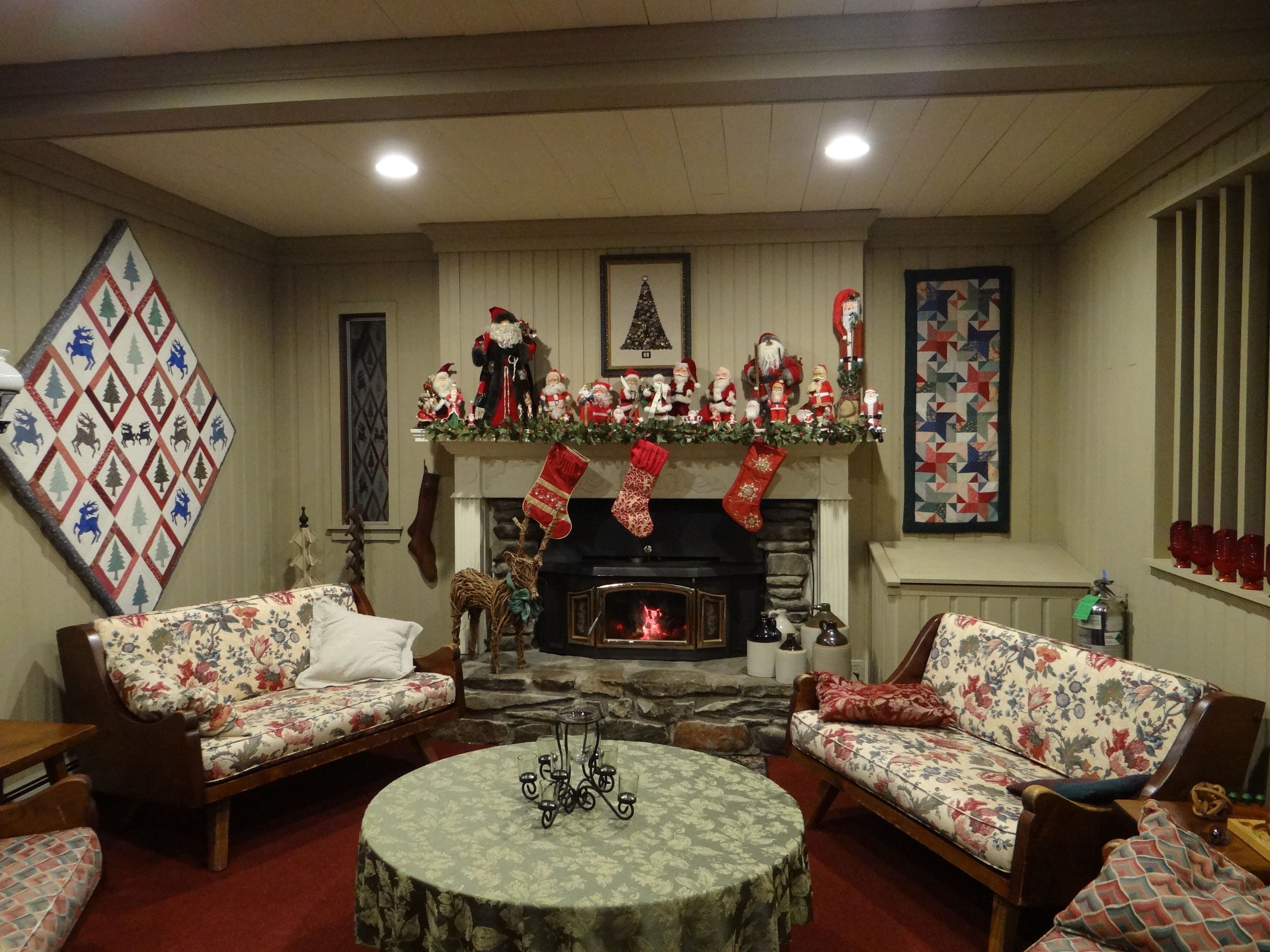 A cozy living room with a fireplace, two floral sofas, a round coffee table, and holiday decorations.