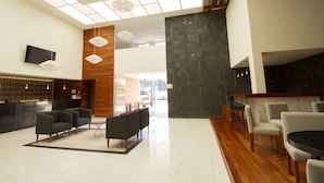 A modern lobby with a reception desk, seating area, and a stone accent wall. - Hotel Posada Señorial (San Andrés Cholula)