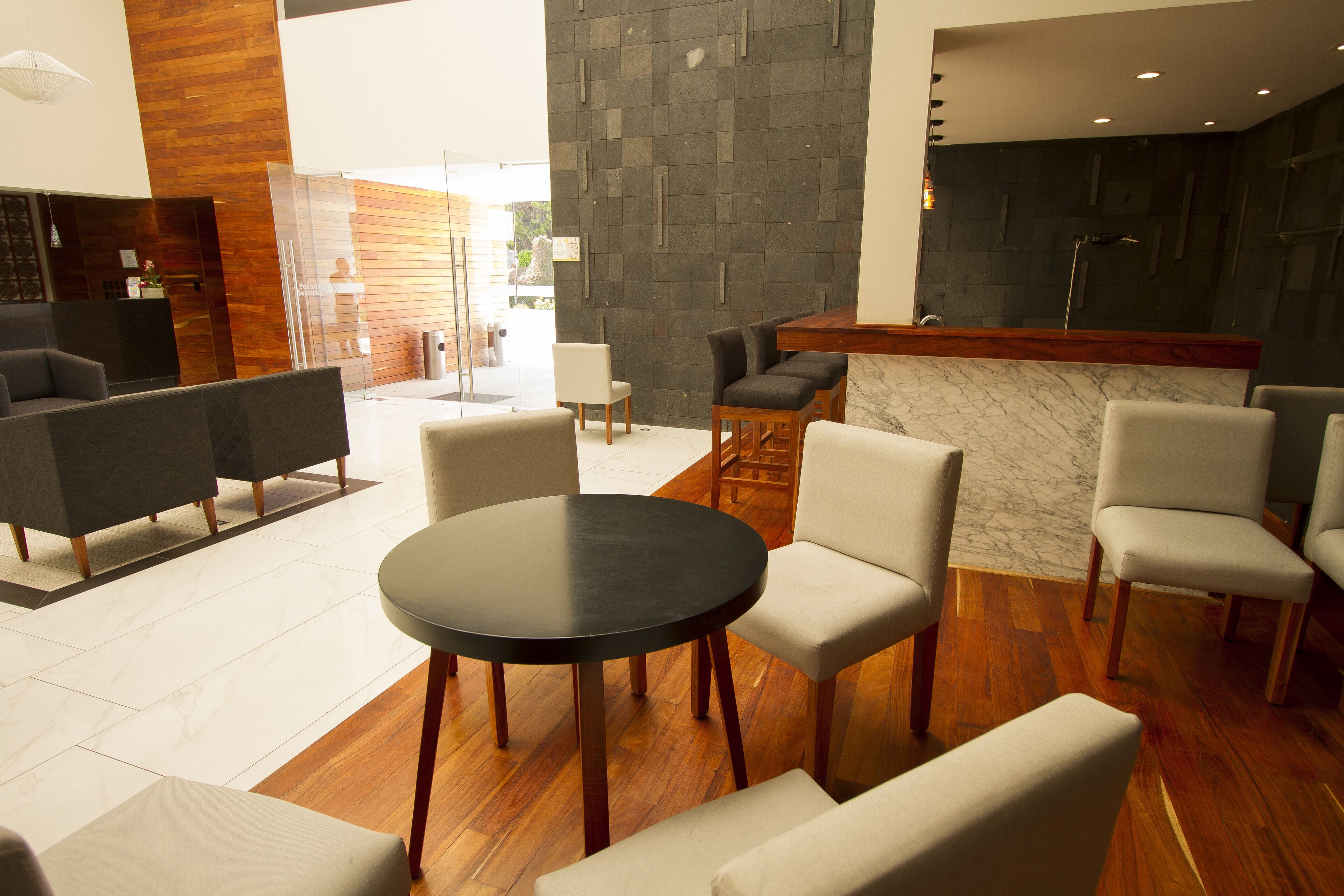 A modern hotel lobby with a reception desk, seating area, and a marble accent wall.