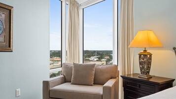 Una habitación con sofá, lámpara y vistas a un paisaje urbano a través de amplios ventanales.