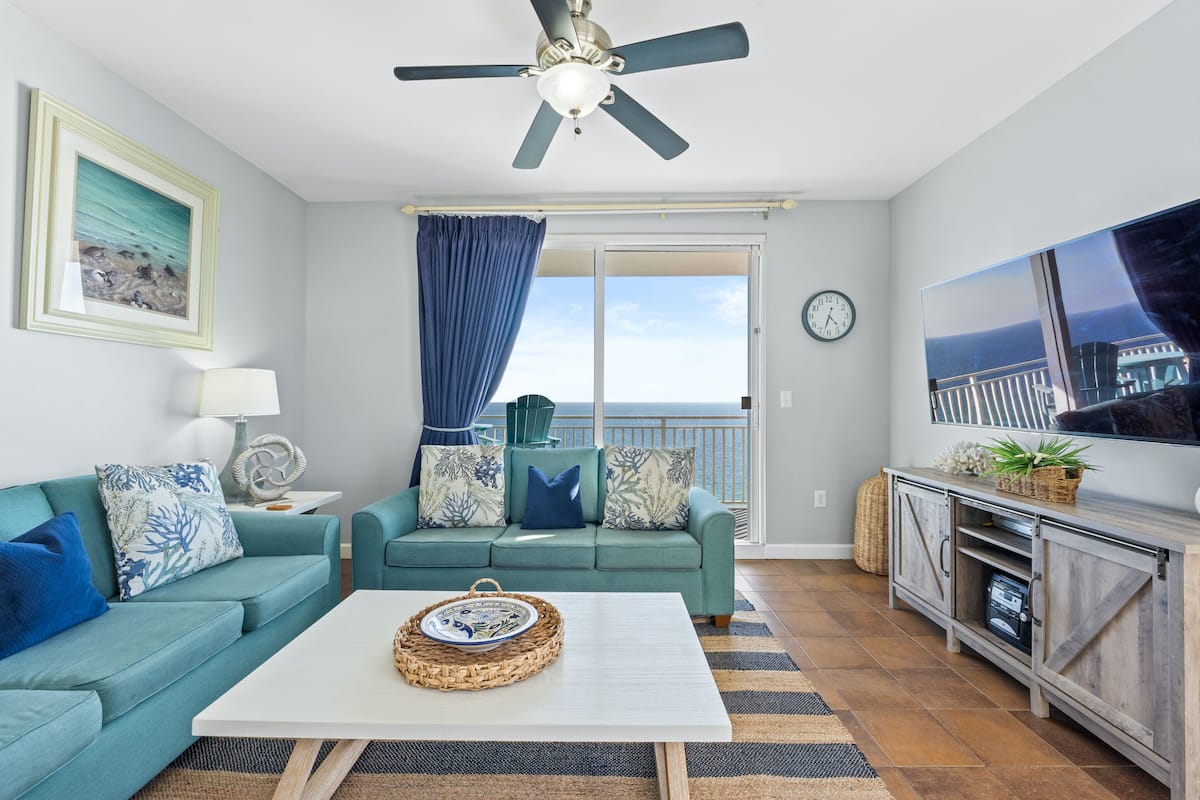 A living room with a teal sofa, a white coffee table, and a TV on a wooden cabinet.