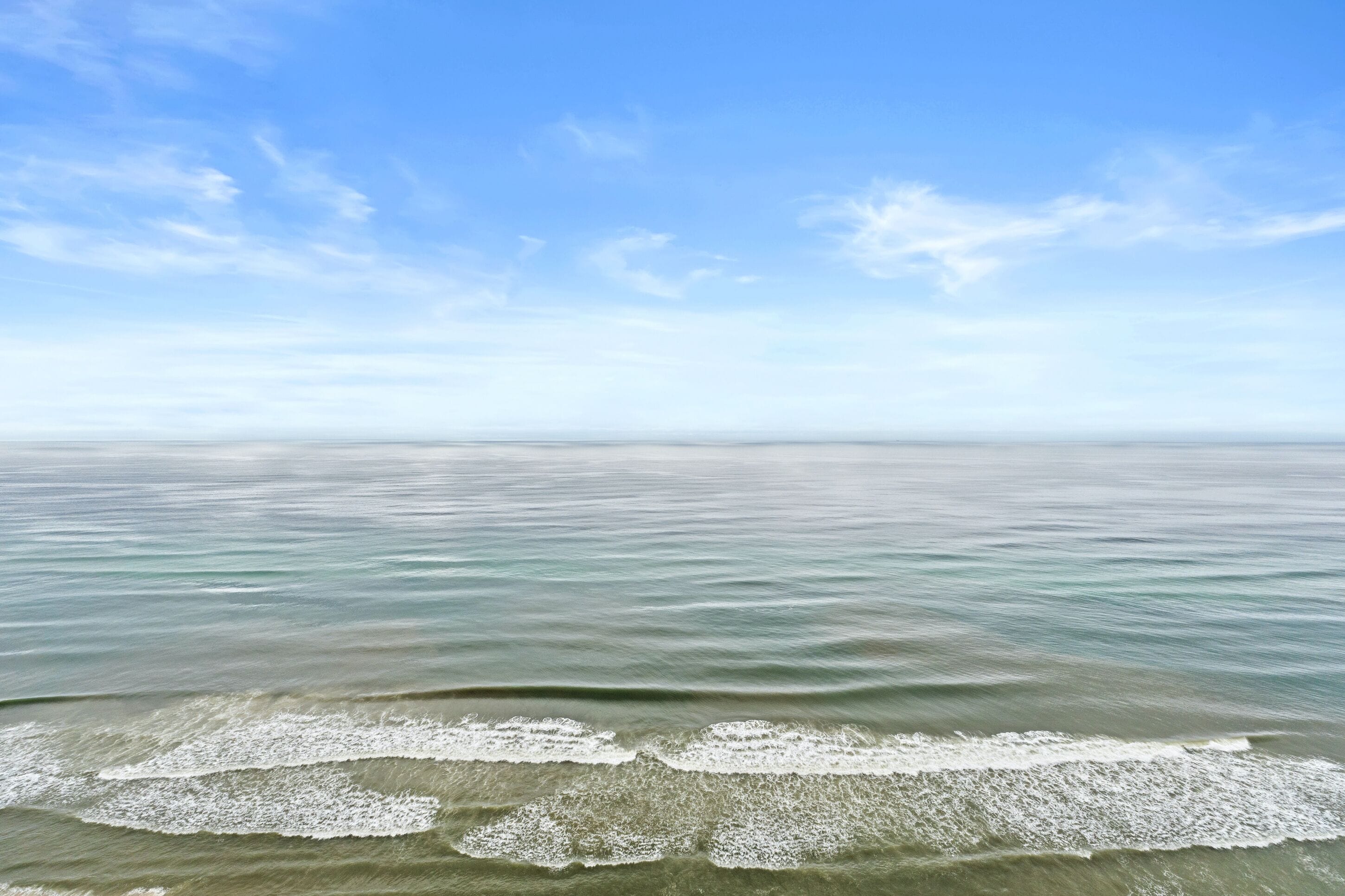 A calm sea with gentle waves and a clear sky.