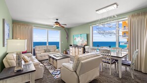 A spacious living room with a large window, a ceiling fan, and a television. - Splash Beach Resort by Panhandle Getaways (Panama City Beach)
